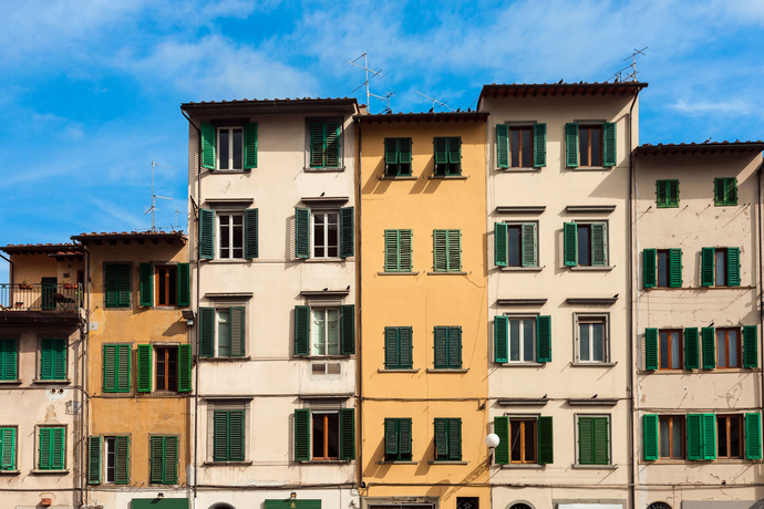 row of italian houses in shades of yellow and ochre with green shutters in Florence, italy