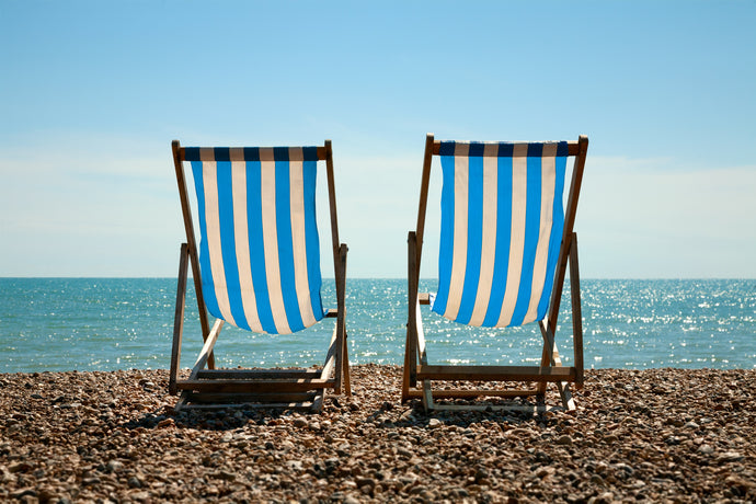 color photo of blue striped beach chairs on brighton beach england