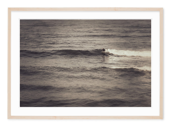 neutral tone fine art photo of surfer riding a wave