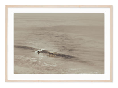 neutral tone fine art photograph of a surfer riding a wave