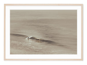 neutral tone fine art photograph of a surfer riding a wave