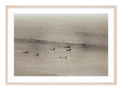 neutral tone fine art landscape of group of surfers heading out to catch waves