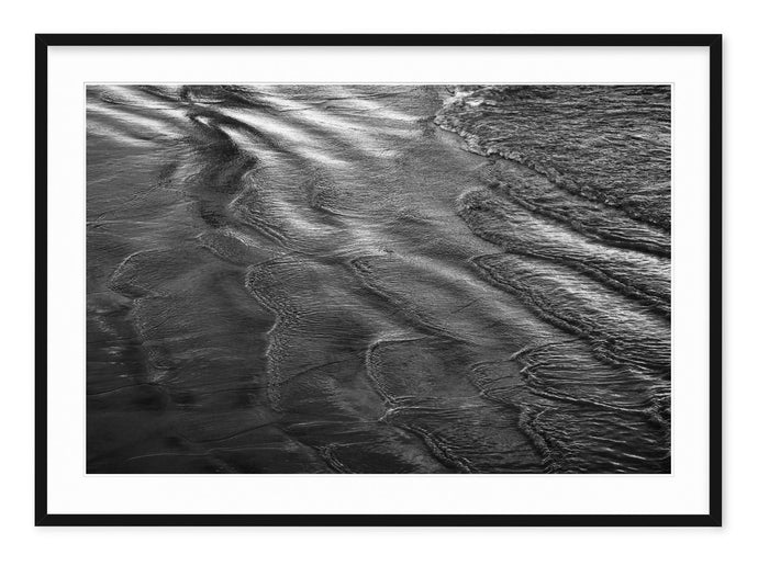 black & white coastal photograph of ripples and waves in the sand
