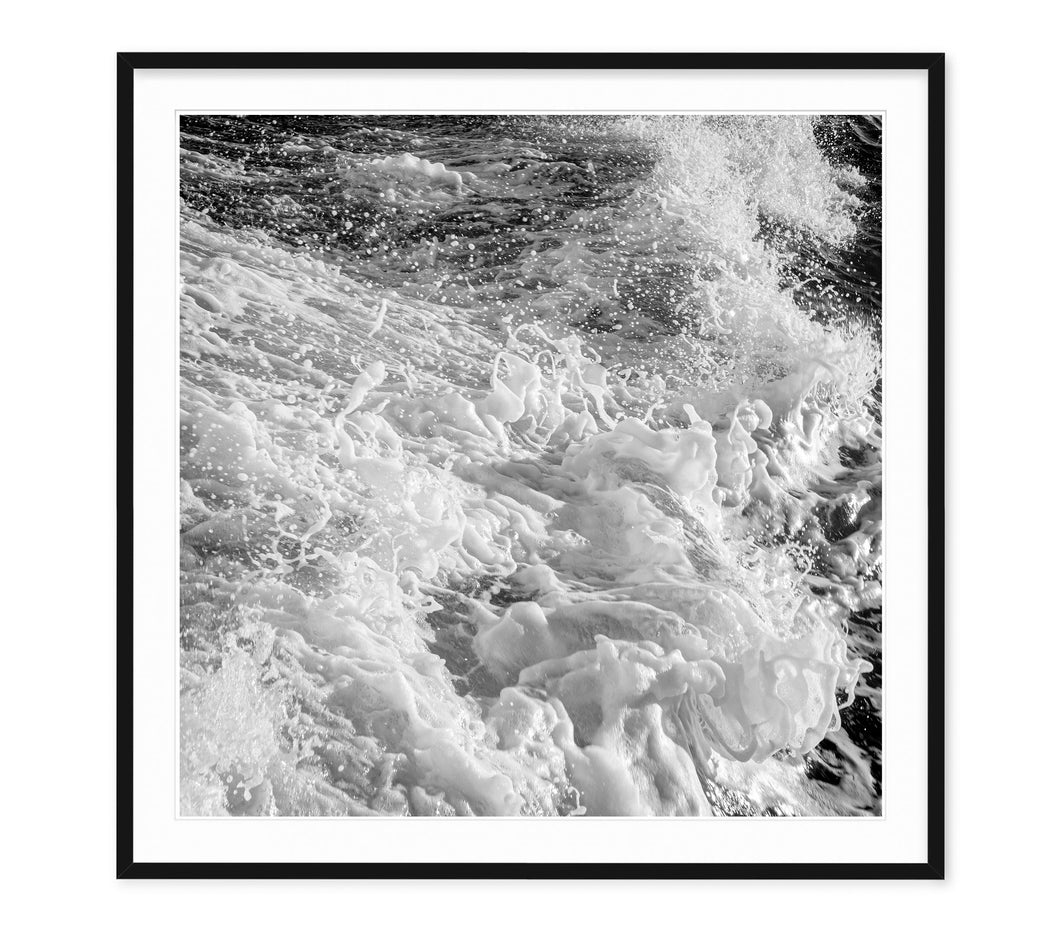 black and white image of foamy waves churning and splashes frozen in mid air